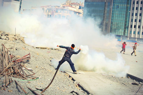 A protestor throws a tear gas canister back towards police.