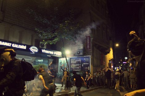 A protestor throwing a tear gas canister back towards the police.