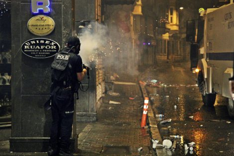 A police officer firing tear down the street towards protestors.