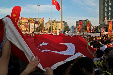 Protestors carry a large Turkish flag through Taksim Square.