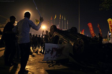Protestors dancing around a destroyed police car at the entrance to Gezi Park.